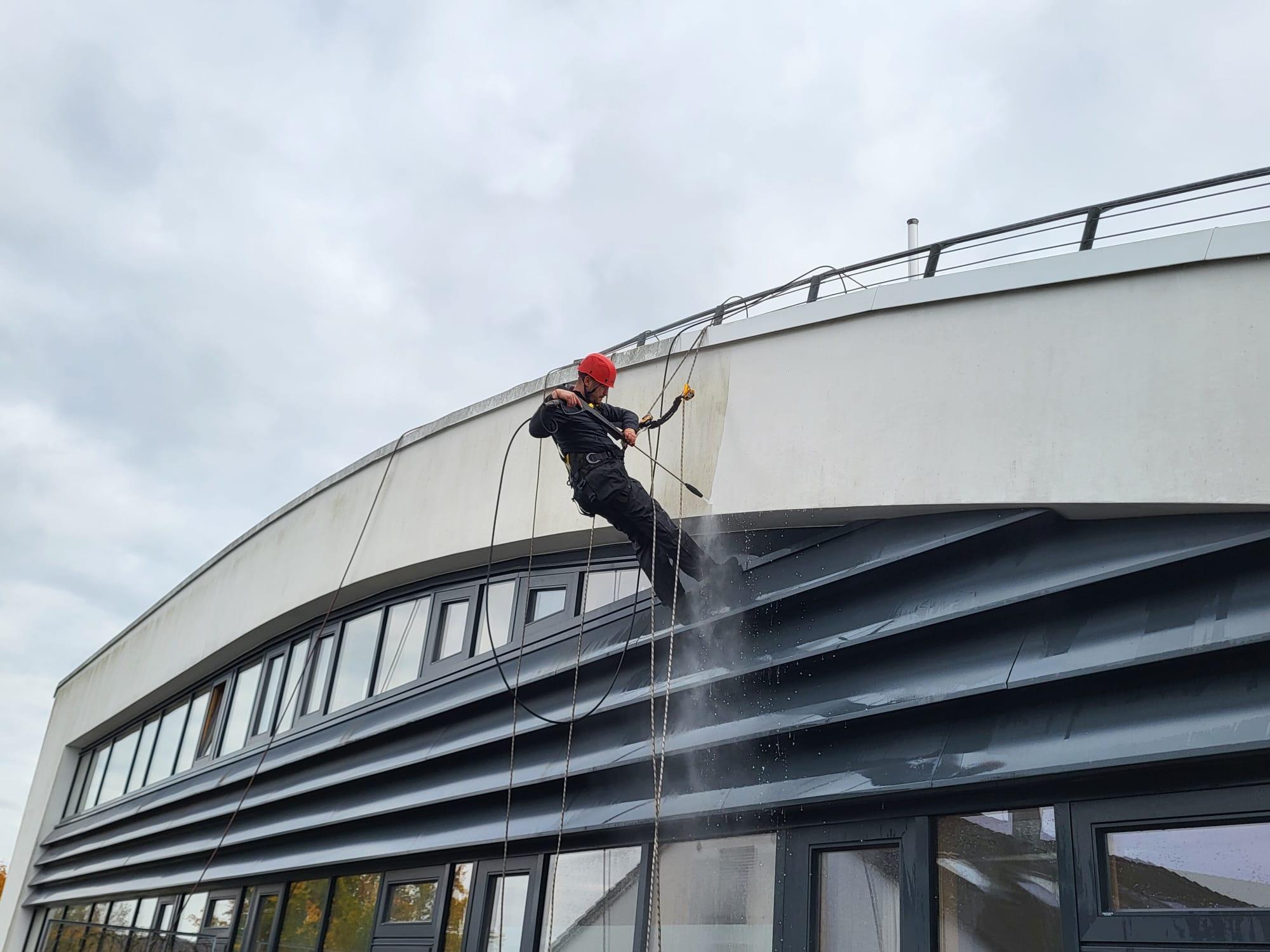 Industriekletterer am Seil an einer gebogenen Dachkante