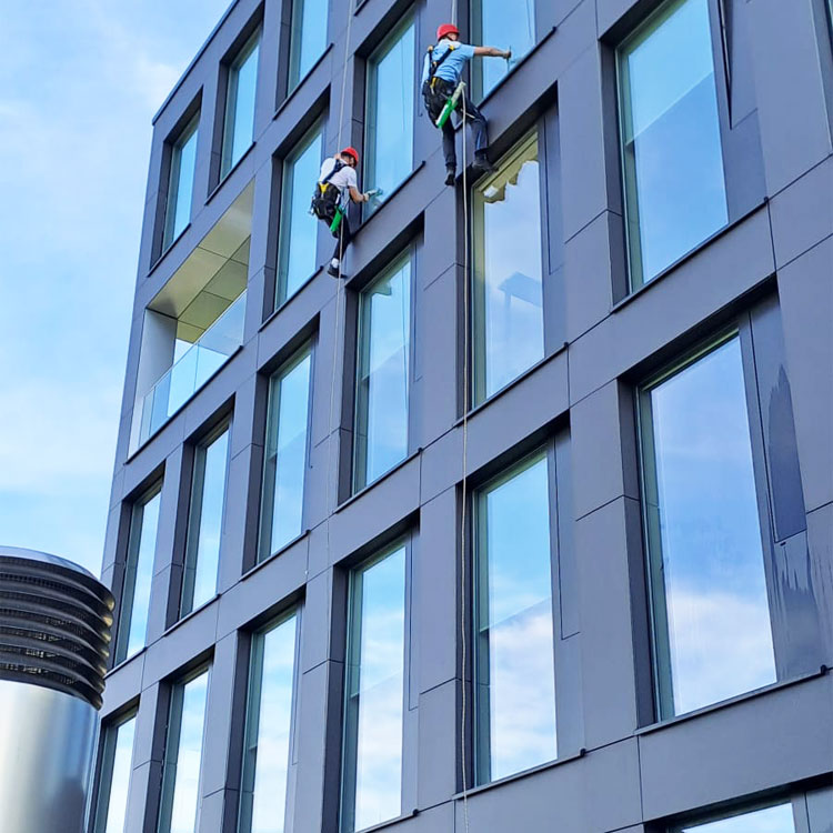 Industriekletterer am Seil an einer Gebäudefassade